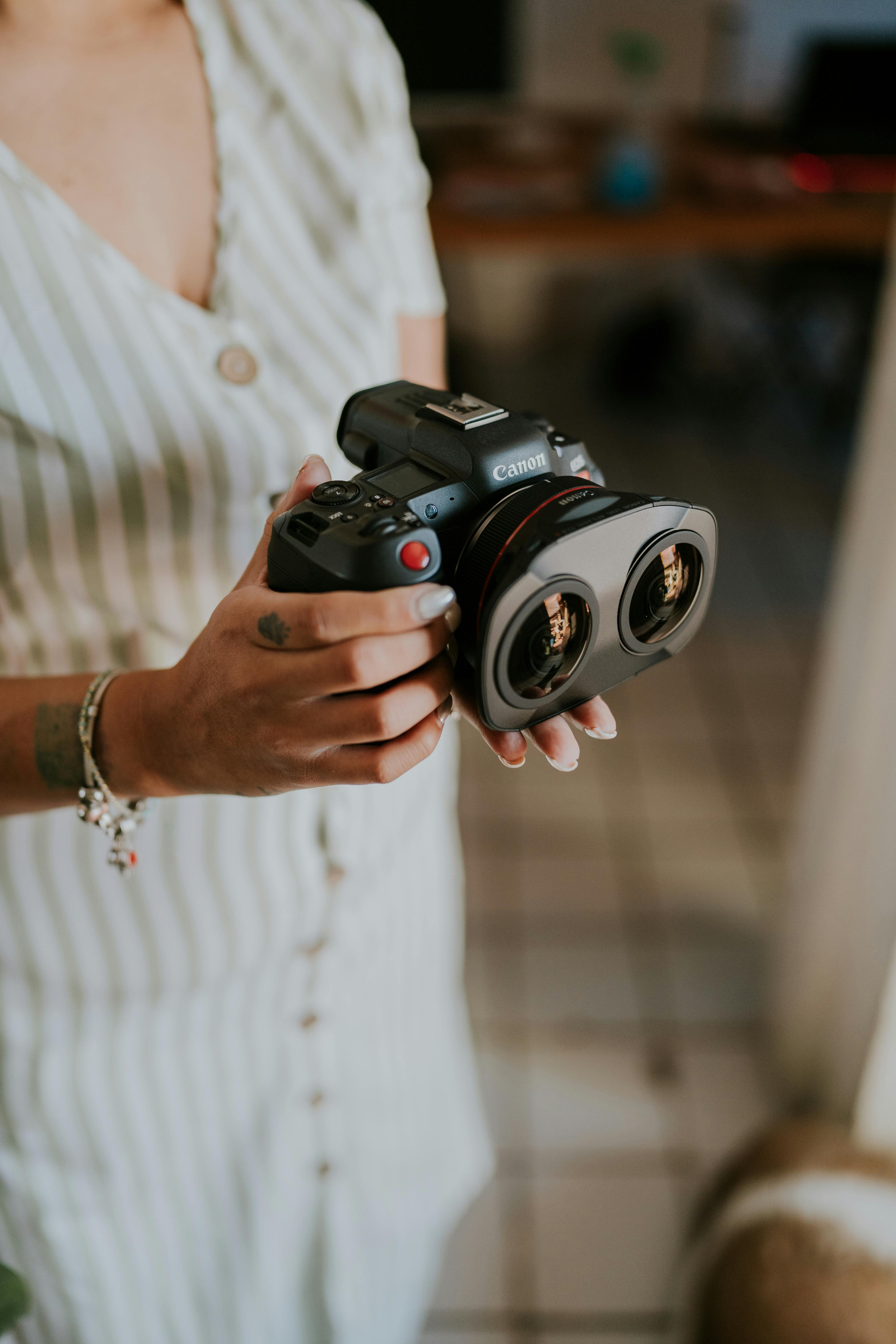 Close-up of a woman holding a dual lens camera indoors.