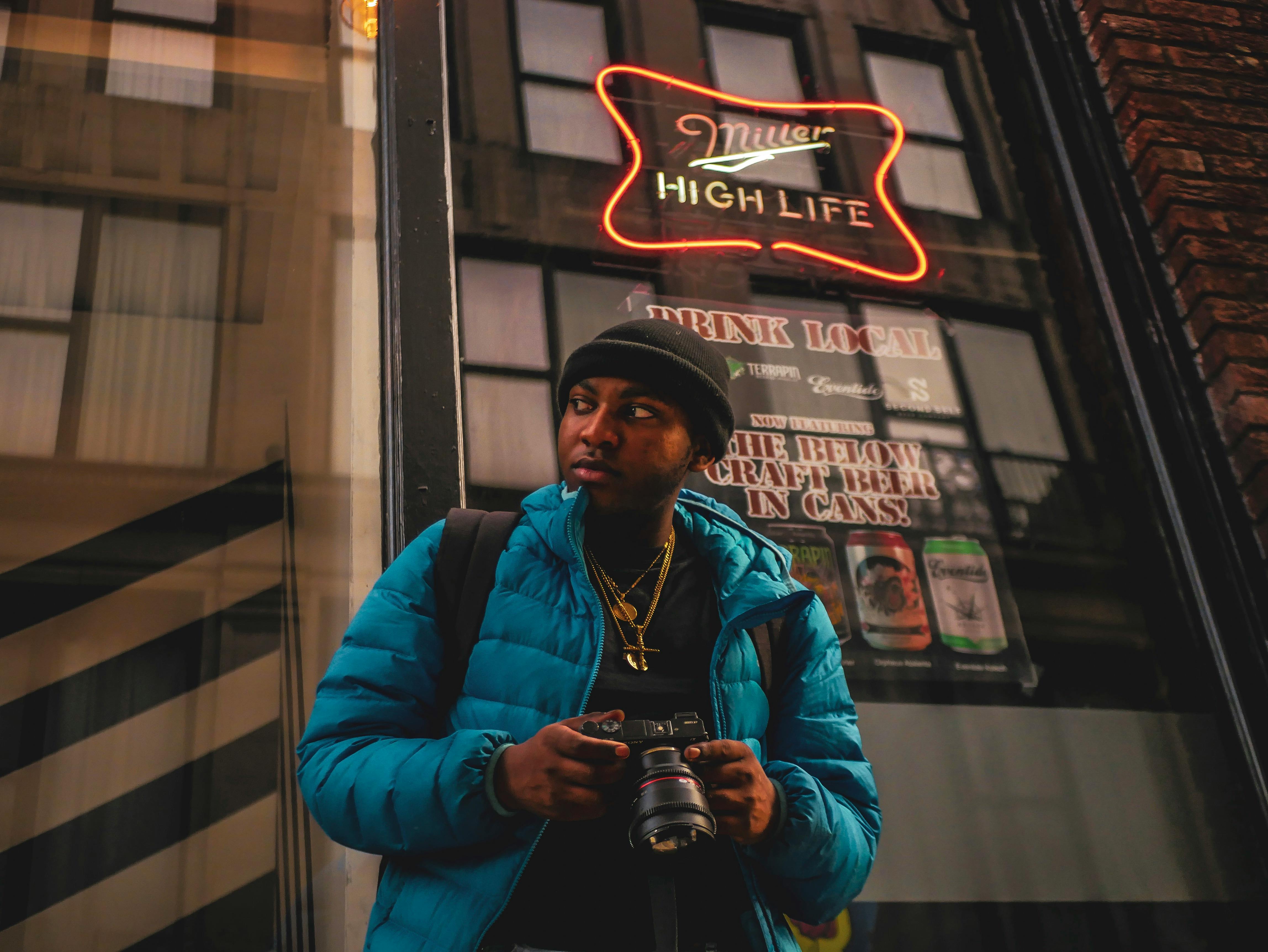 man holding digital camera standing in front of glass door