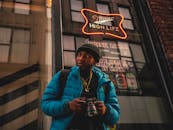 一名成年男性摄影师在城市霓虹灯前拿着相机