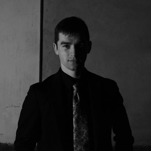 A man in a suit and tie standing in a dark room