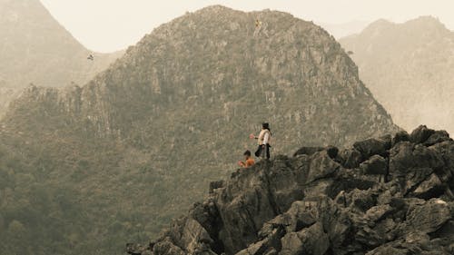 Woman and Man on Rocks on Hill with Mountains behind