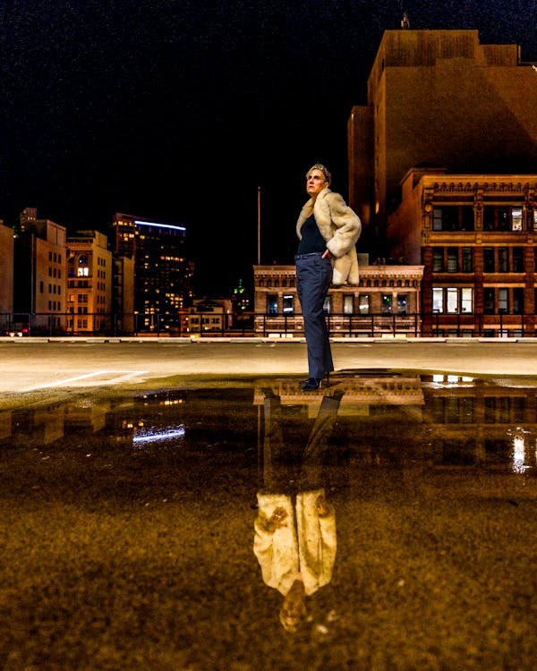 Nighttime Woman Standing in Pool of Reflecting Water in the City