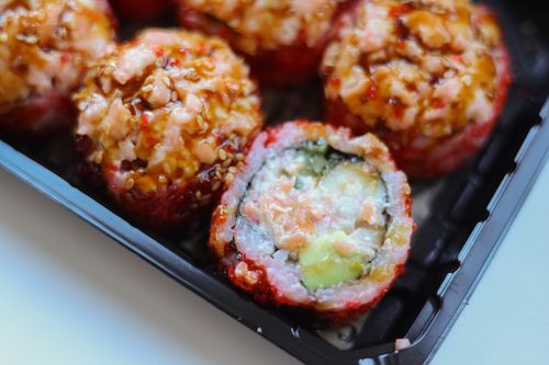 Free Vibrant sushi rolls with sesame seeds and glaze in a plastic container, showcasing fresh ingredients. Stock Photo