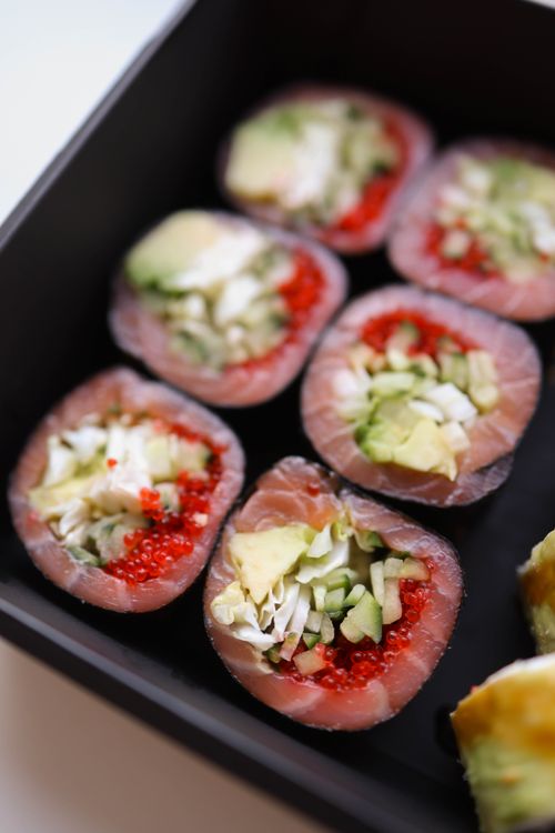 Free Close-up of salmon sushi rolls in a black box, featuring avocado and roe. Stock Photo