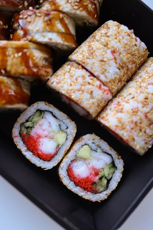 Free Close-up of a sushi platter featuring diverse rolls topped with sesame seeds and fish eggs. Stock Photo