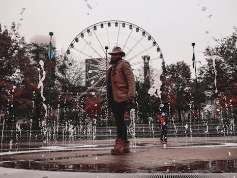 一名时尚男子带着摩天轮，在城市公园的喷泉旁摆姿势