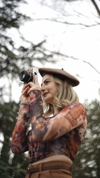 Stylish woman with beret, using a camera in an outdoor setting. Perfect for lifestyle and fashion photography.