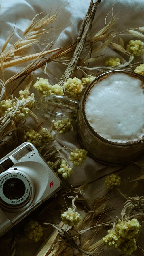 A camera and a cup of coffee on a bed