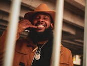 一名戴着帽子、留着胡须、面带微笑、戴着鼻环的男子在户外手持智能手机