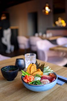 A vibrant seafood bowl served in a contemporary restaurant setting, showcasing fresh ingredients and artistic presentation.