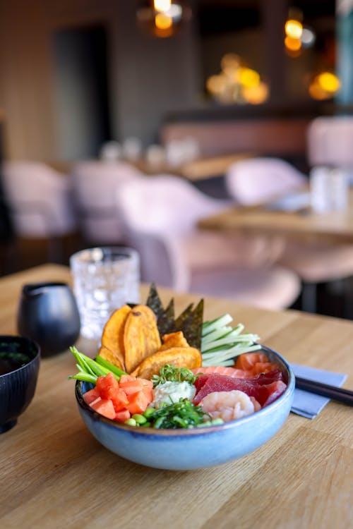 A bowl of food sits on a wooden table