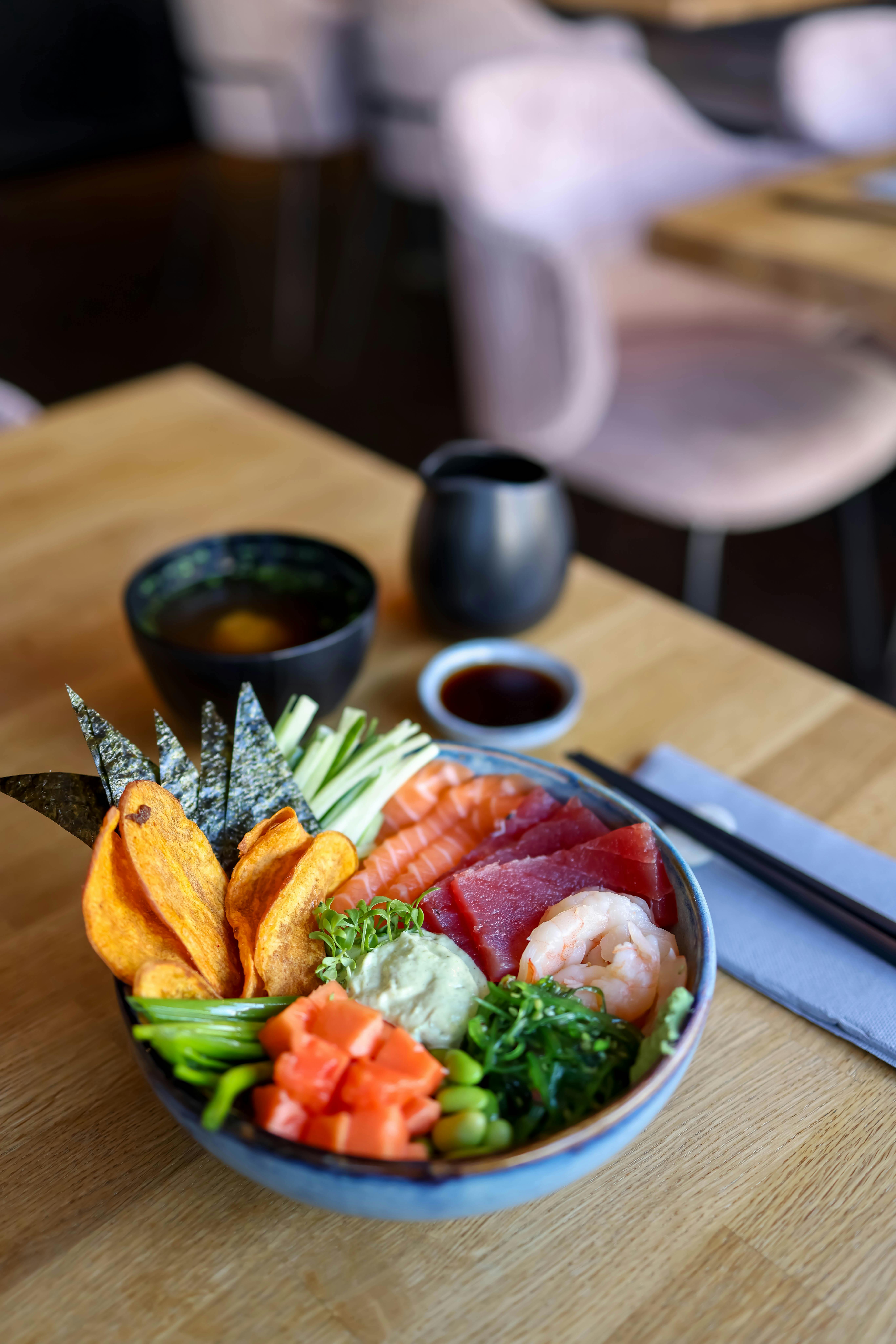Colorful seafood poke bowl with salmon, tuna, and fresh vegetables on a wooden table.