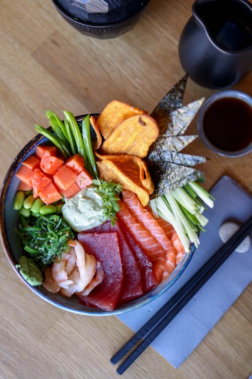 A bowl of sushi with chopsticks and a spoon