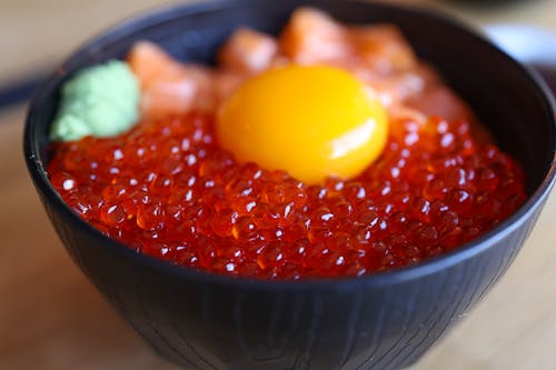 A bowl of red cavia with an egg on top