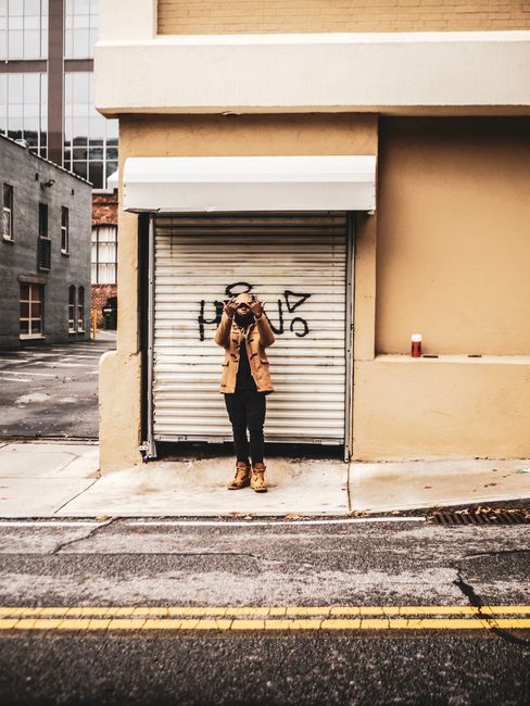 A fashionable man poses in an urban setting for a street photography session.