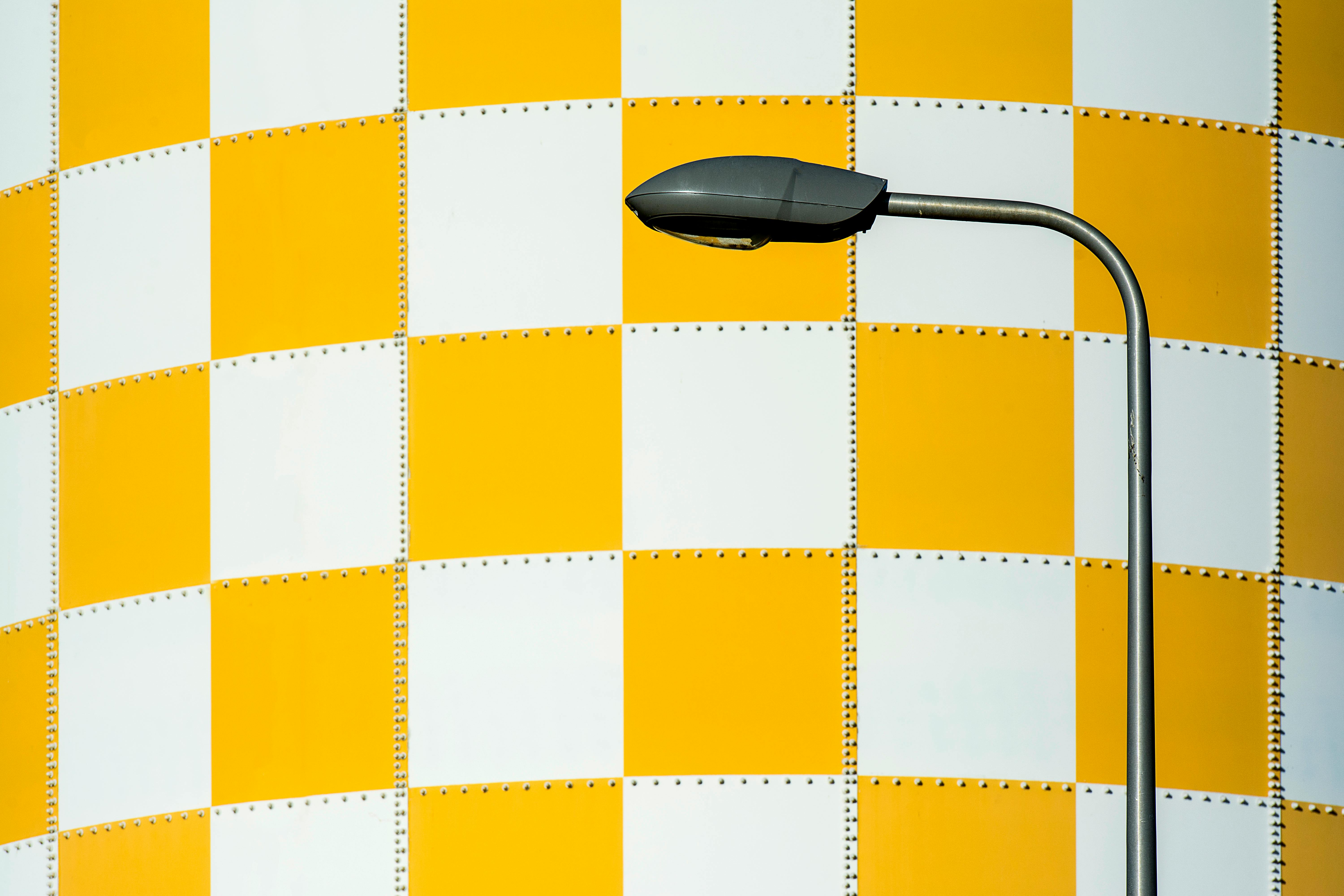 Street lamp in front of a yellow and white checkered wall with ample copyspace.