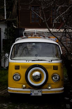 Classic yellow Volkswagen van parked in a lush Istanbul yard, evoking nostalgia and adventure.