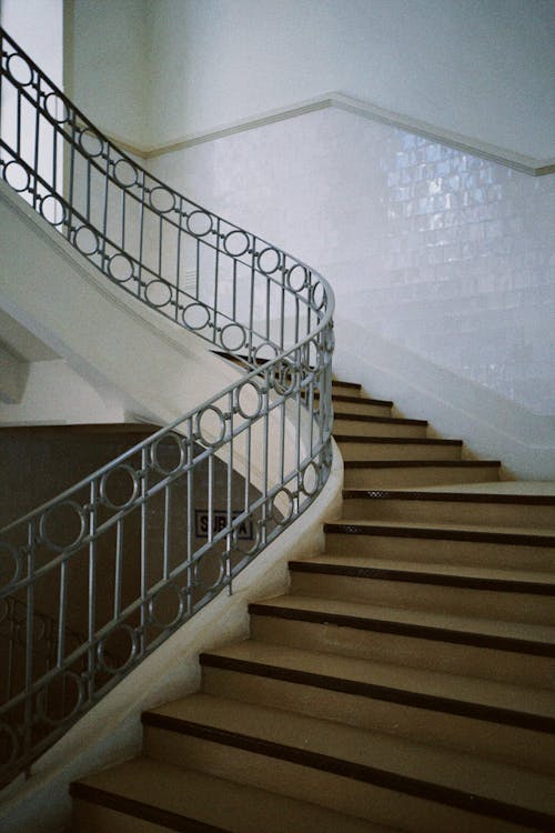 A stairway with wrought iron railing and a white wall