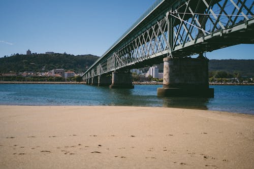 A bridge over a sandy beach with a body of water