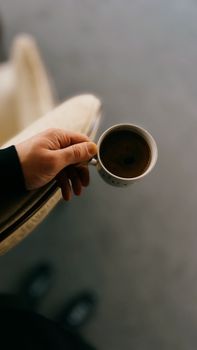 Close-up of a hand holding a coffee cup. Simple and cozy morning vibe.