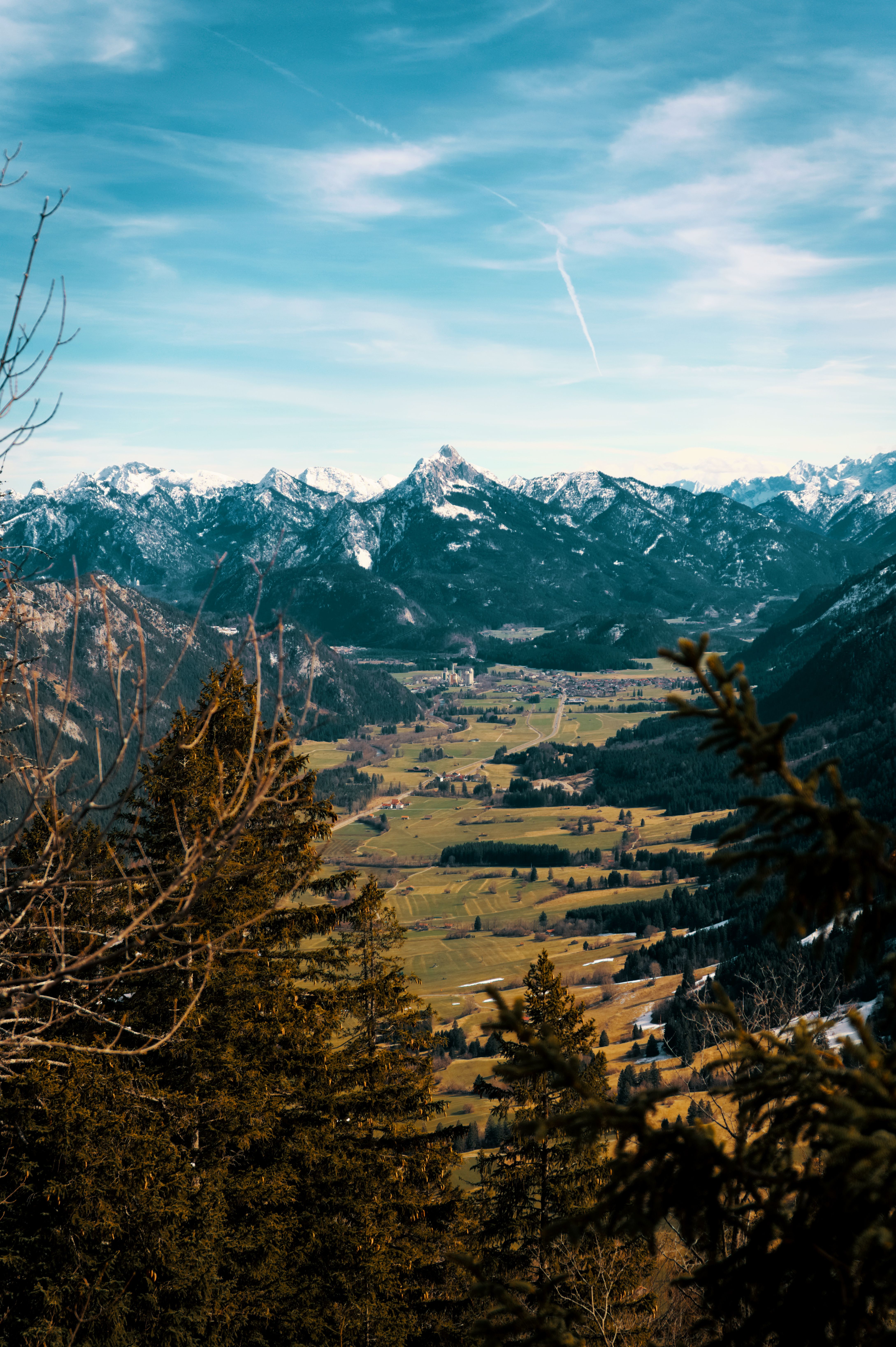 Picturesque landscape of Pfronten, Germany with emerald green valley and majestic snow-covered mountains.