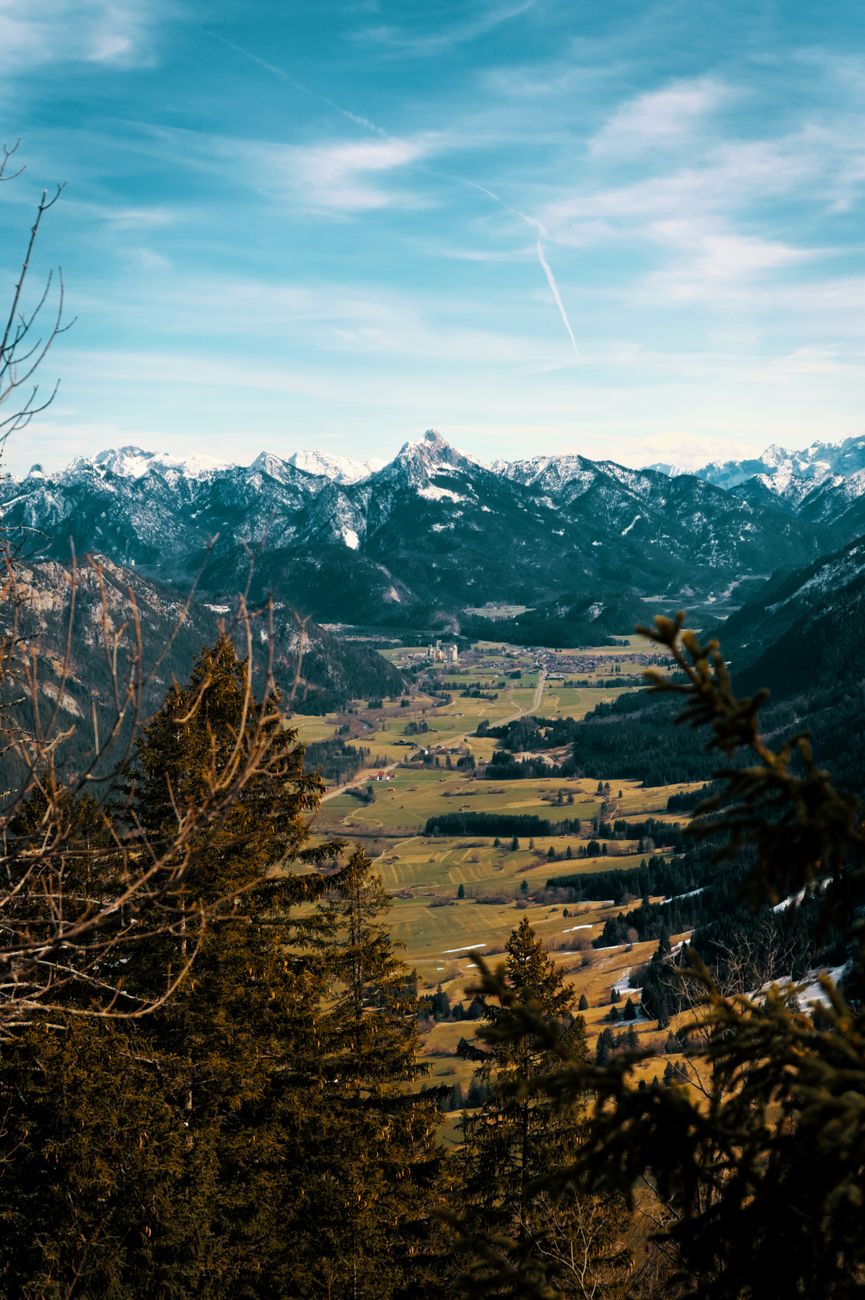 Picturesque landscape of Pfronten, Germany with emerald green valley and majestic snow-covered mountains.