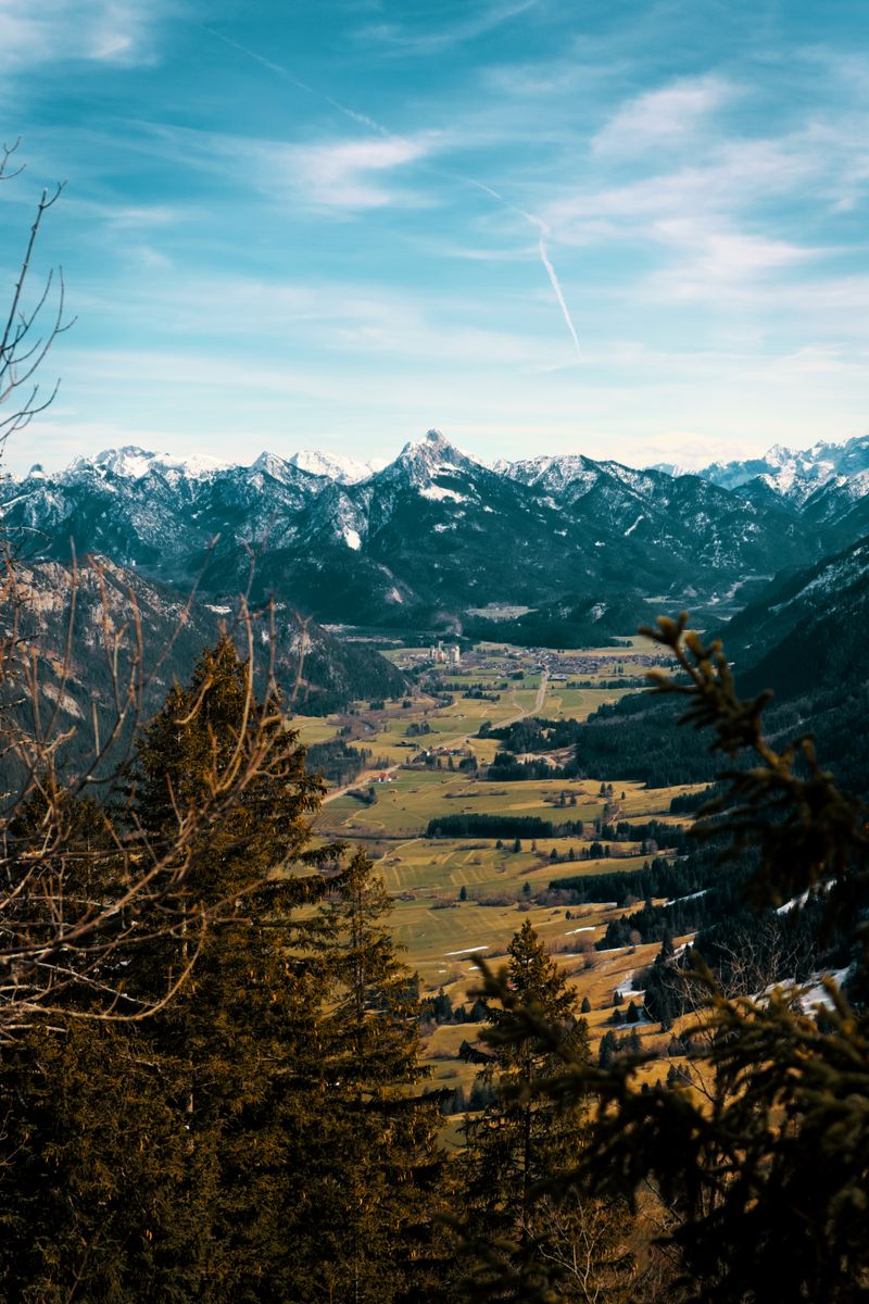 Picturesque landscape of Pfronten, Germany with emerald green valley and majestic snow-covered mountains.