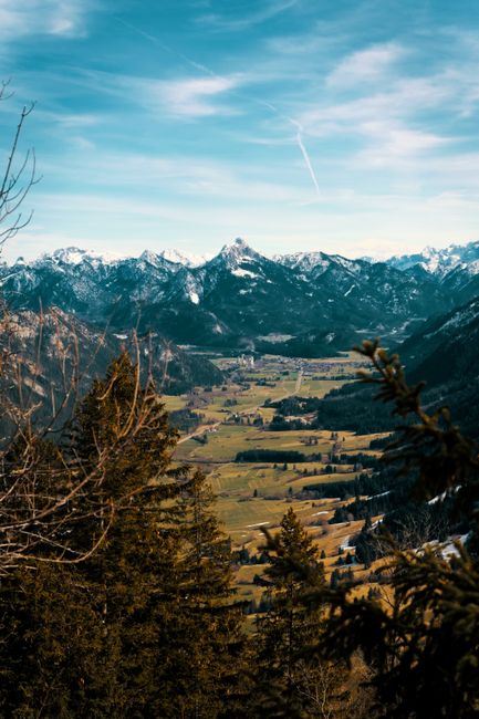 Picturesque landscape of Pfronten, Germany with emerald green valley and majestic snow-covered mountains.