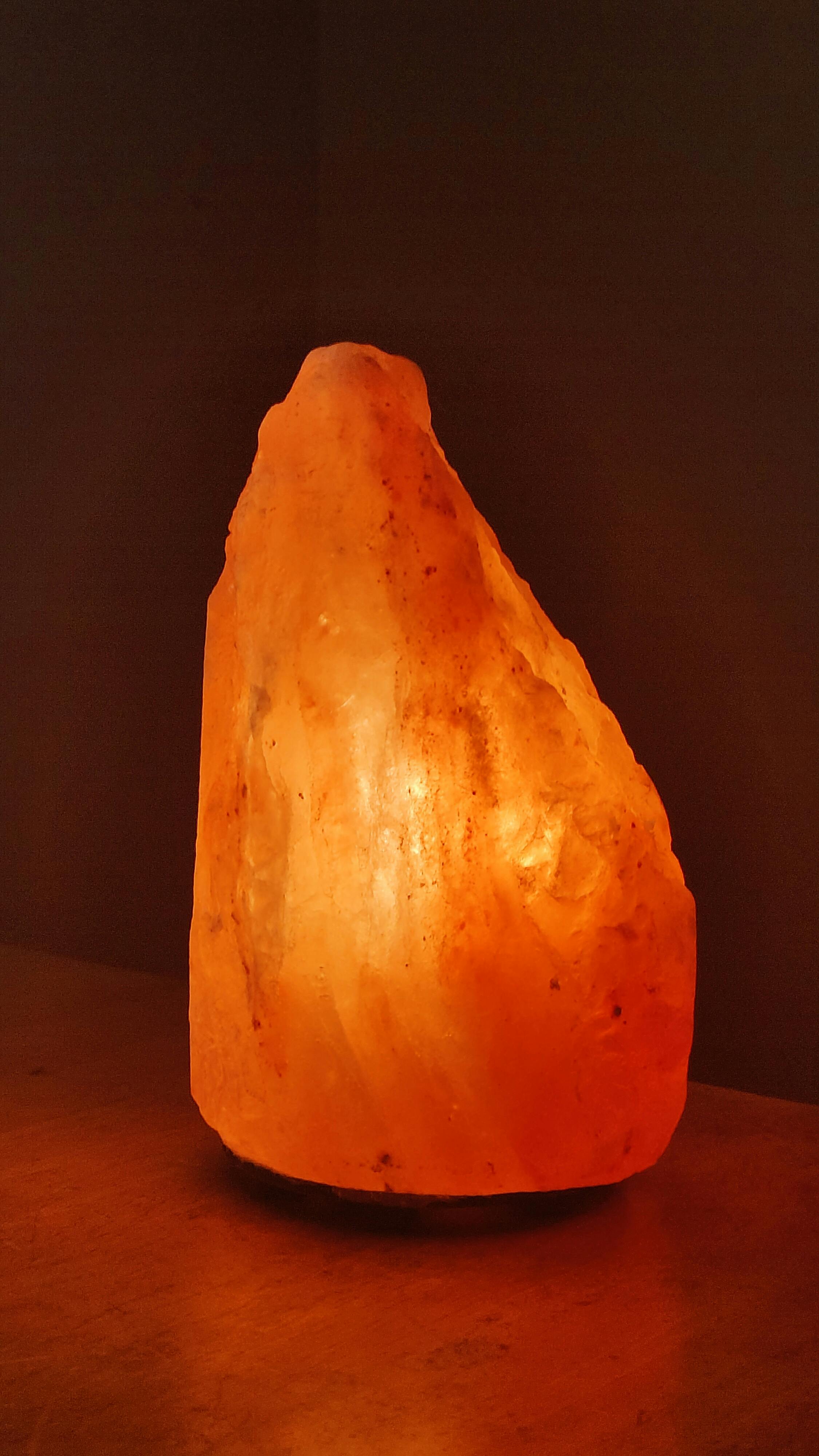 Warm glow of a Himalayan salt lamp creating a calming ambiance on a wooden table.