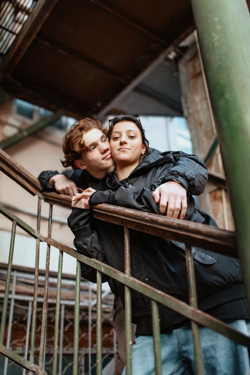 Two people leaning on a railing in an industrial area