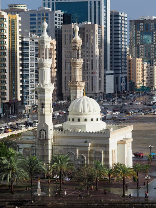 A mosque in the middle of a city with tall buildings
