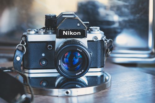 Free Close-up of a classic Nikon camera displayed on a reflective surface, highlighting its vintage appeal. Stock Photo