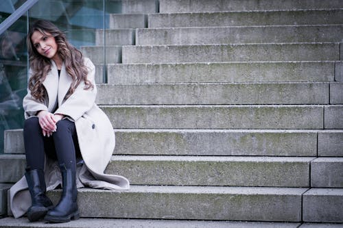 A woman sitting on some steps wearing a coat