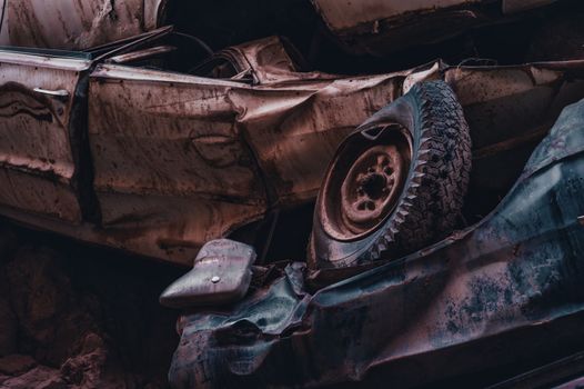 A dramatic view of stacked, rusty and abandoned cars in a junkyard, showcasing decay and abandonment.
