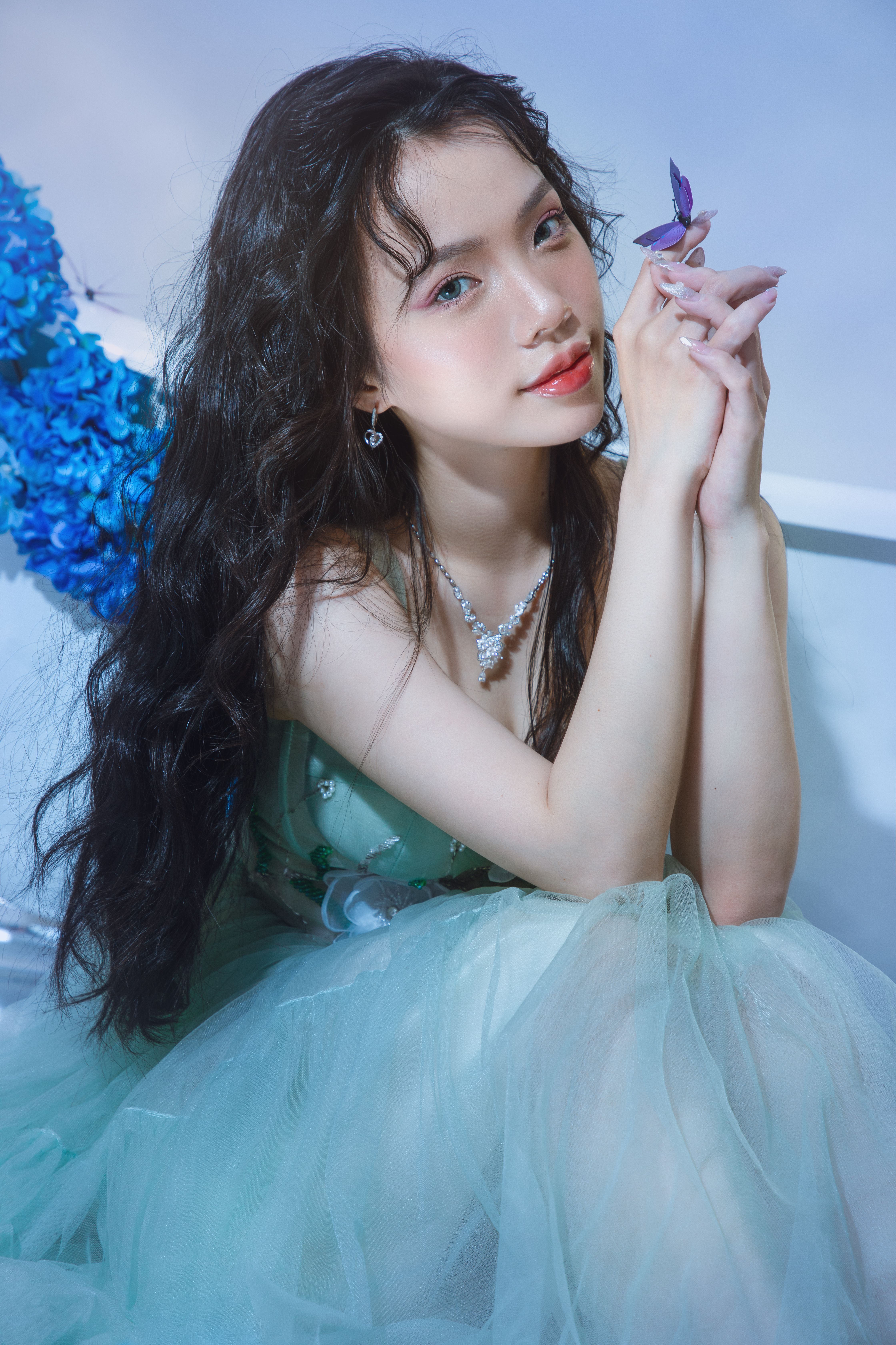 Portrait of a woman in a green dress, holding a butterfly, exuding elegance and beauty.