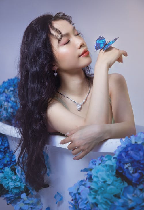 A woman in blue flowers holding a butterfly