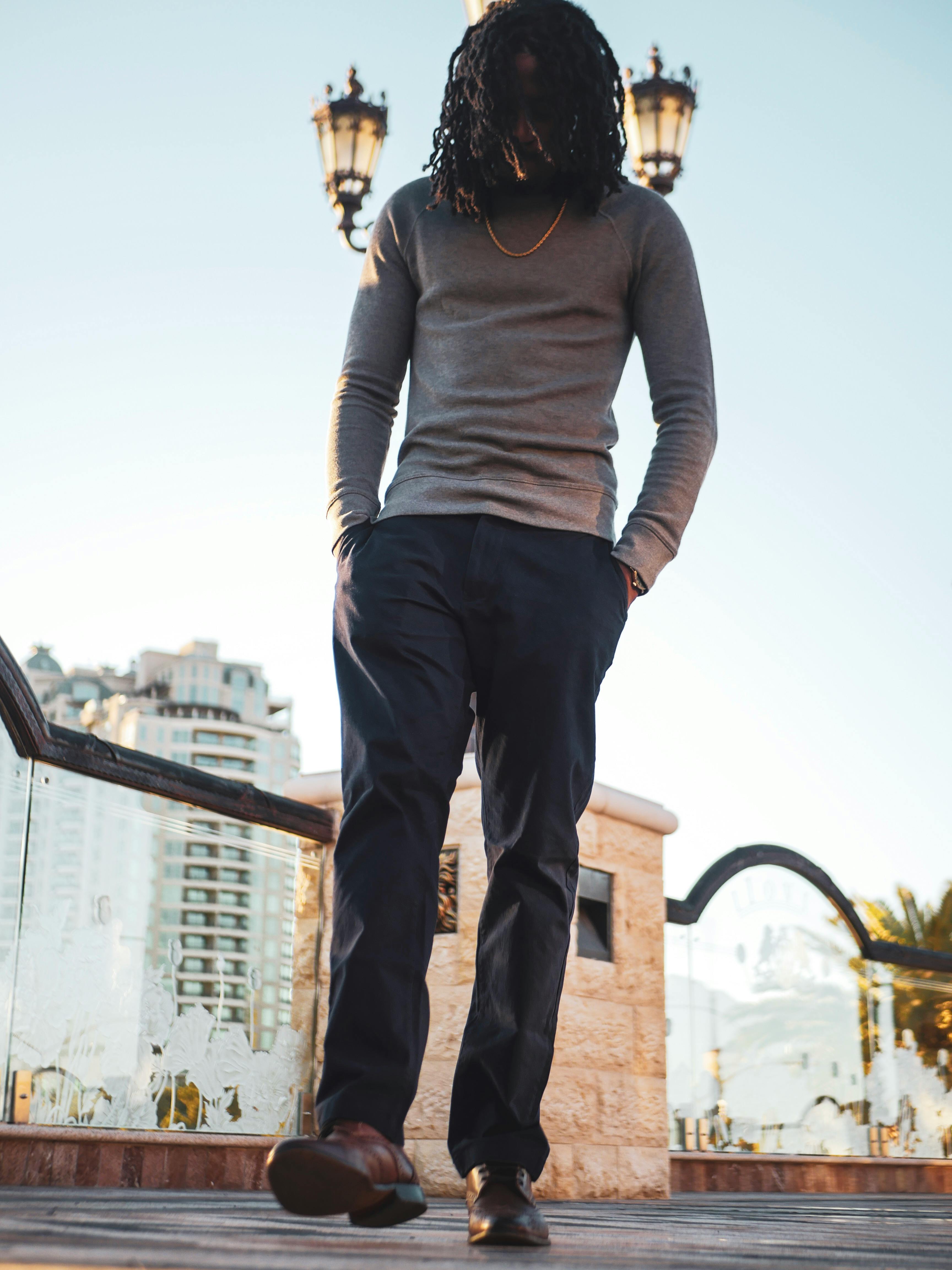 一名男子在城市户外随意行走，周围有路灯和现代建筑