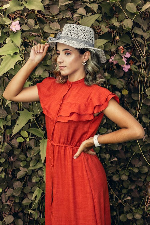 A woman in a red dress and hat posing for a photo