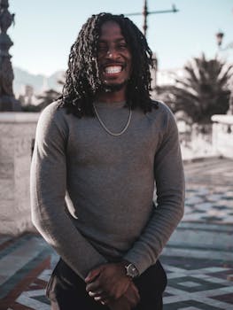 一个快乐的扎辫子男人站在铺着瓷砖的小路上，享受着户外阳光明媚的一天