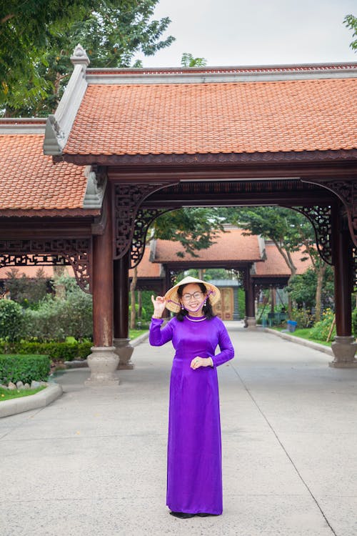 Young Woman Wearing a Purple Ao Dai Standing in Front of Gates 