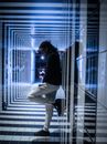 一名男子靠在未来派走廊的墙上，走廊里有几何图案和反光表面