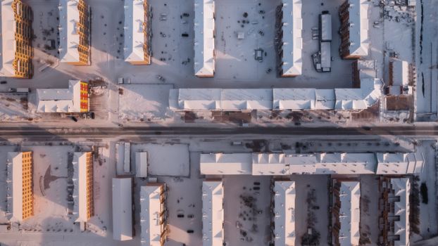 Overhead view of snow-covered urban buildings in winter, creating a geometric pattern.