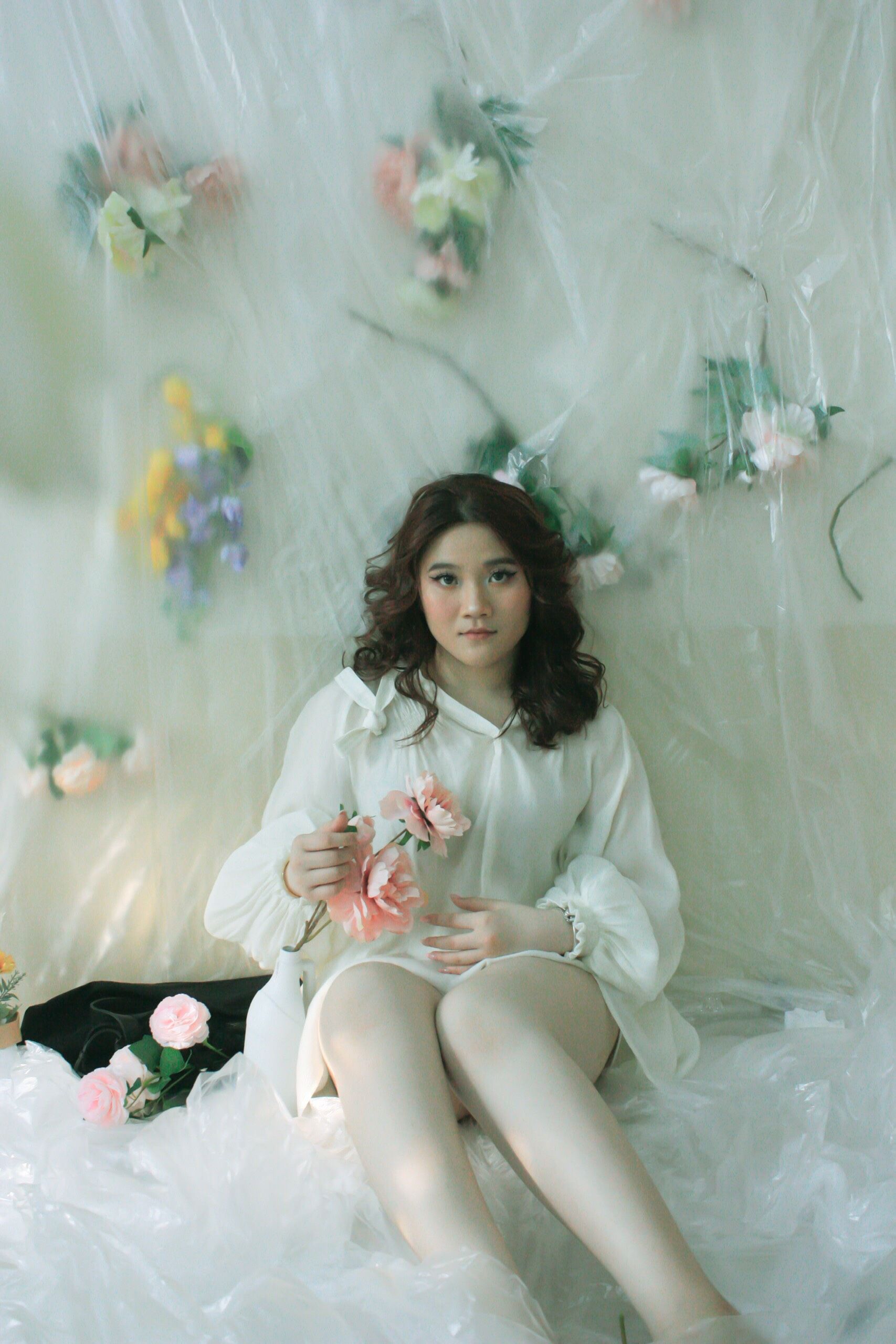 Young Woman in a White Dress Sitting and Holding Flowers · Free Stock Photo