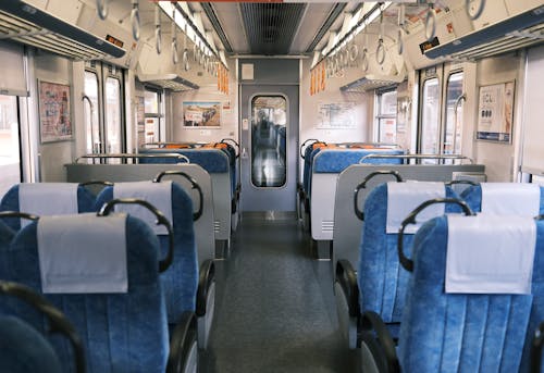 The inside of a train with blue seats and white walls