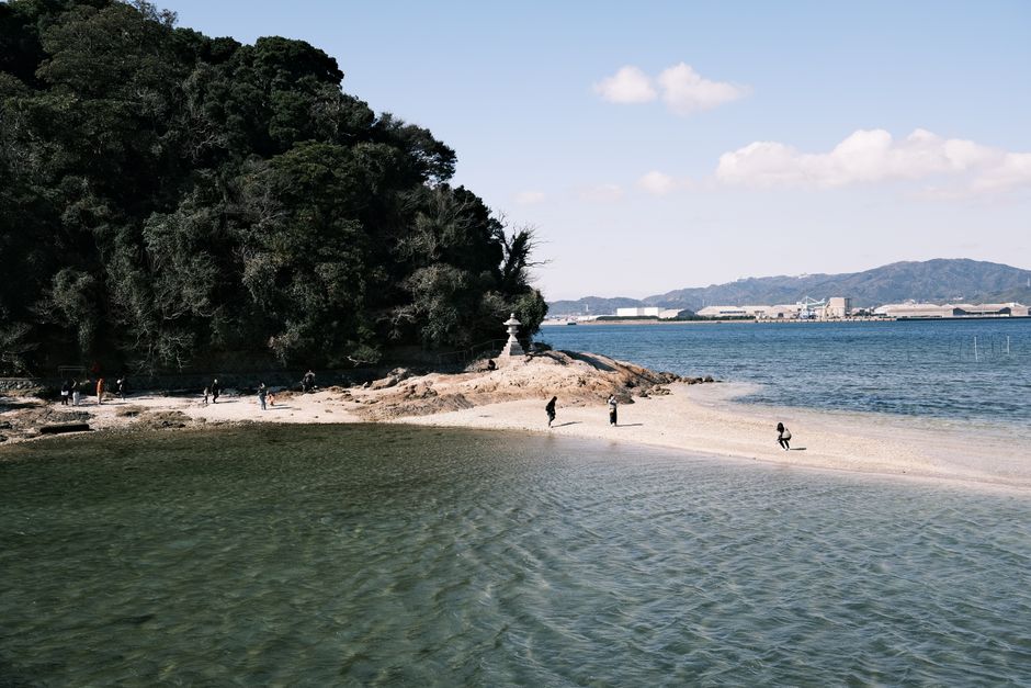 Explore the tranquil seaside view of Gamagōri, Aichi, Japan with distant cityscapes and sandy islands.