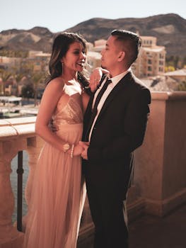 一对衣着优雅的浪漫情侣，在阳光明媚的阳台上相拥，背景是连绵的山脉