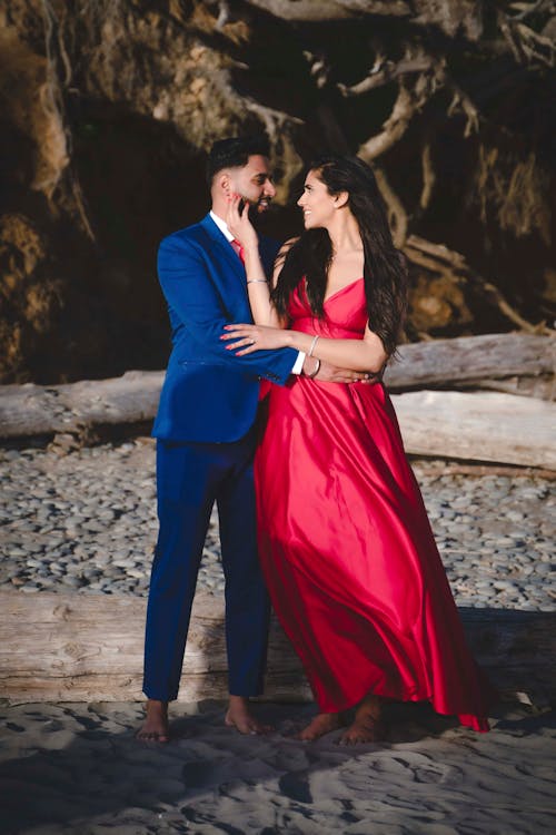 A couple in red dresses standing on a beach