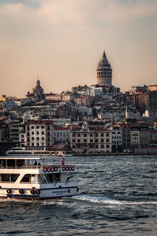 Free Ferry crossing the Bosphorus with Istanbul's historic Galata Tower in the backdrop at sunset. Stock Photo