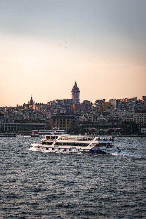 Free The iconic Galata Tower with a ferry on the Bosphorus, capturing İstanbul's cityscape at sunset. Stock Photo