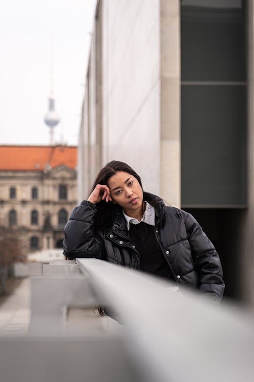 A woman leaning against a railing in front of a building